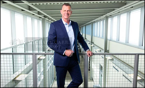 Houston personal branding portrait of a business professional standing in a modern office setting with natural light.