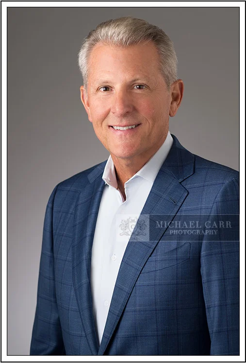 Classic corporate headshot of Houston executive in blue jacket