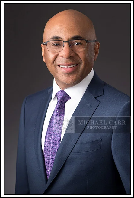 Houston Headshot Photographer Executive portrait of a CEO in a blue suit and purple tie photographed in a Houston studio