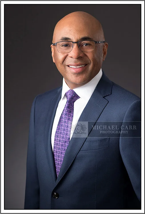 Houston Headshot Photographer Executive portrait of a business leader in a blue suit and purple tie photographed in a Houston studio