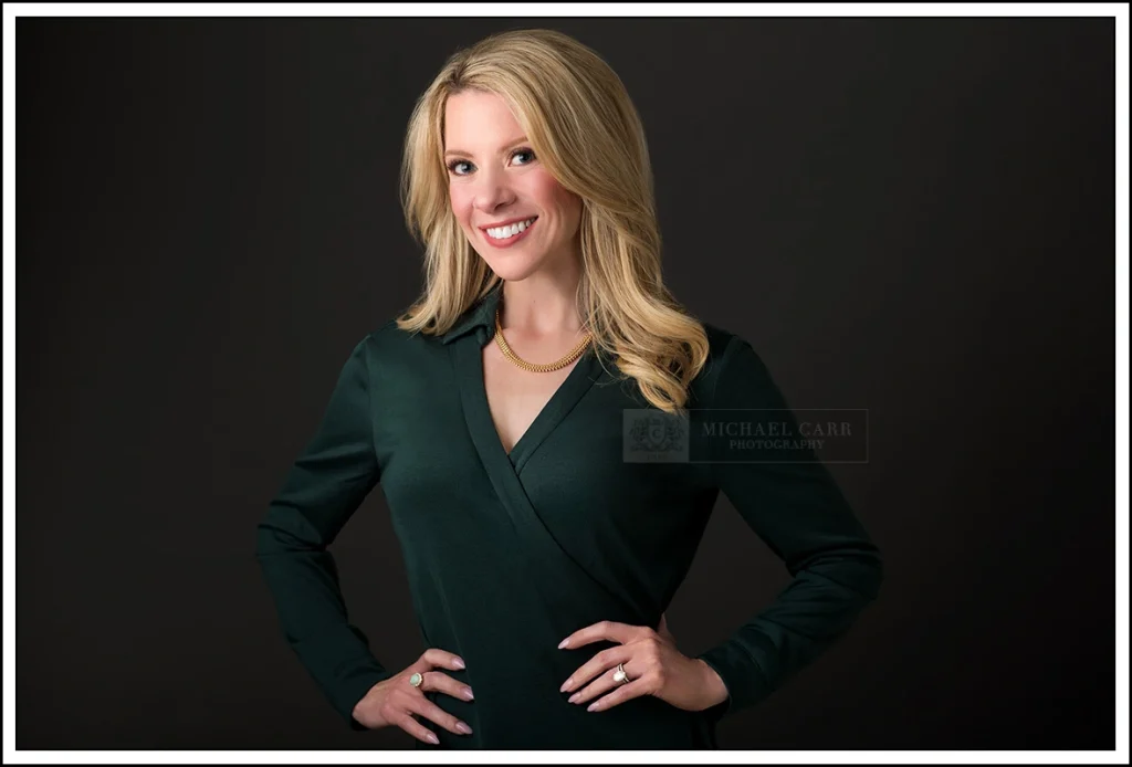 Business professional photographed against a classic dark studio backdrop, illustrating how to choose a headshot background.